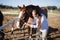 Vet adjusting horse bridle at barn during sunny day