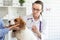 The vet makes a dog an injection syringe. The owner keeps the dog. Blurred background of veterinary clinic.