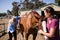 Vet with woman checking horse while standing on field