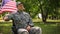 Veteran saluting, sitting in wheelchair, waving flag behind, independence day