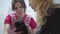 Veterinarian checking ears of small black dog holded by his owner close up. After cecking another nurse give food to the