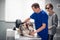 A veterinarian is checking the health state of a guide dog in his office, the dogs owner is in the background