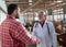 Veterinarian and farmer shaking hands in cow stable