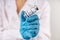 Vial with COVID-19 vaccine against coronavirus infection in the hand of a doctor in a nitrile glove on a white background. Close-