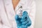 Vial with COVID-19 vaccine against coronavirus infection in the hand of a doctor in a nitrile glove on a white background. Close-