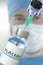 Vial with placebo medicine and syringe against blurred doctor`s face. 3D rendering