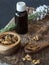 Vial of propolis, wooden bowl and spoon of propolis granules on piece of wood.