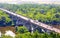Vibrant aerial view of a river arch automobile stone bridge with moving cars in summer