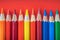 Vibrant array of colorful pencils on bold red backdrop for creative art projects
