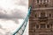 The vibrant azure metal fragment of the famous Tower Bridge in London hanging from one of the two main towers of the bridge