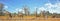 Vibrant busy waterhole with Giraffes, zebras and Sable Antelopes against a natural bush background and blue cloudy sky, Hwange