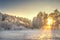 Vibrant Christmas winter landscape on sunrise. Warm sunlight in morning winter nature. Frost and fog in clear sunny morning.