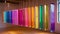 Vibrant colored chimes hang in a row creating a visual representation of the harmonious vibrations of sound healing