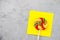 Vibrant, colorful lollipop is illustrated on a grey background, resting atop a yellow sticky note