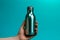 Vibrant cyan backdrop highlights female hand gripping steel water bottle