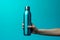 Vibrant cyan backdrop highlights female hand gripping steel water bottle