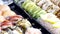 Vibrant display of assorted sushi pieces, showcasing a variety of colors and textures, arranged neatly in black trays.