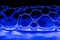 Vibrant display of bubbles on the side of a glass backlit by a blue LED light