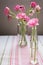 Vibrant display of pink flowers in clear vases featured atop a striped tablecloth.