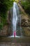 Vibrant Elegance: Girl Cloaked in Red near the Waterfall