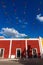 Vibrant flag chains over bright blue sky along red colonial building, Valladolid, Yucatan, Mexico