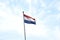 Vibrant flag of Netherlands waving against a clear blue sky depicting an iconic and patriotic scene