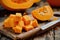 Vibrant Fresh Pumpkin Chunks on a Rustic Wooden Cutting Board with a Sharp Knife