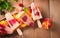 Vibrant fruit popsicles on a wooden table, surrounded by fresh peaches and raspberries, radiating a refreshing summer vibe