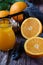 Vibrant glass of orange juice displayed with freshly-sliced oranges on a black tabletop