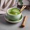 A vibrant green matcha latte in a ceramic cup with a bamboo whisk beside it4