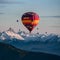 Vibrant hot air balloons soar above majestic mountain peaks