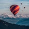 Vibrant hot air balloons soar above majestic mountain peaks