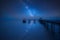 Vibrant Milky Way composite image over landscape of old pier stretching out to sea