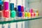 vibrant nail polish bottles in a row on glass shelf