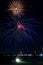 Vibrant night sky illuminated by an array of colorful fireworks bursting above a lake