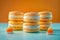 Vibrant Orange Flavored French Macarons On A Soft Blue Background With Candy Corn Accents