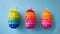 Vibrant paper fringed Easter egg pinatas hanging against soft blue background.