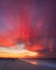 Vibrant pink and orange clouds streak across the sky as the sun rises above a coastline - copy space. Long Island NY