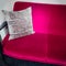 Vibrant pink velvet sofa with ornamental cushion