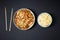 Vibrant plate of shrimp salad, bowl of rice with egg and chopsticks on black background. Take away food