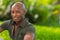 Vibrant portrait a handsome young African American man smiling at the camera. Man is posing outdoors in a park setting