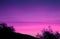 Vibrant Purple Pink Sky over the Foliage and Hill Silhouette