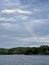 Vibrant rainbow arcs across the serene surface of a tranquil lake and lush woods