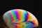 Vibrant, rainbow-hued soap bubble against a dark background.