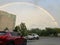 Vibrant rainbow over a cityscape, numerous buildings, and parked cars in the lot