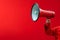 Vibrant red background with a hand holding a megaphone