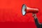 Vibrant red background with a hand holding a megaphone