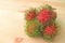 Vibrant Red and Green Fresh Ripe Rambutan Fruits Isolated on Wooden Table