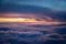 Vibrant red, purple and blue from sunset above the clouds from the window of a plane