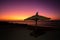 Vibrant red sky at sunset on Anakao beach in Madagascar, with a tropical parasol and sun lounger